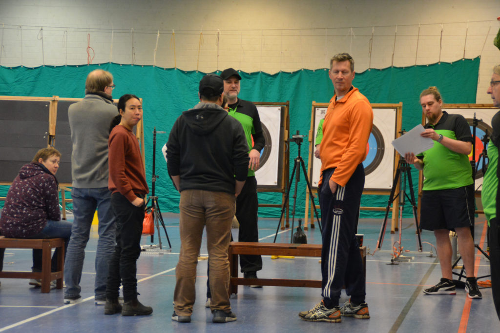 Eine Gruppe von Menschen beim Para-Bogebnschießen Workshop in einer Turnhalle.